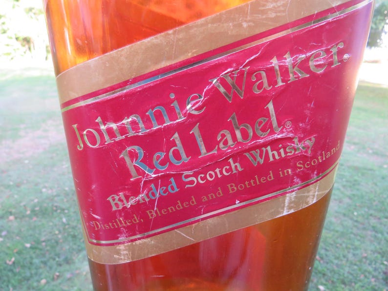 May include: Close-up of a Johnnie Walker Red Label bottle. The red label features gold lettering and a gold border. The text reads "Johnnie Walker Red Label Blended Scotch Whisky".
