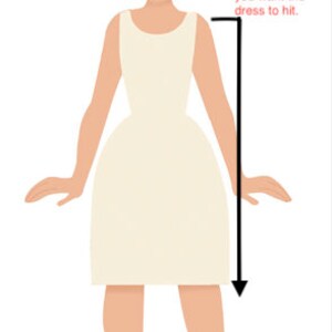 Op de afbeelding: Illustratie van een vrouw die met haar armen langs haar zijde staat. De tekst op de afbeelding luidt "Voor aangepaste lengtematen" en "Met haar staand, recht en haar armen langs haar zijde." Een zwarte pijl wijst naar beneden vanaf de schouder van de vrouw naar haar onderbeen met de tekst "Begin aan de punt van haar schouder en meet naar beneden tot waar je de jurk wilt laten vallen." De tekst "niet voorbij het midden van de kuit" staat onder de pijl.