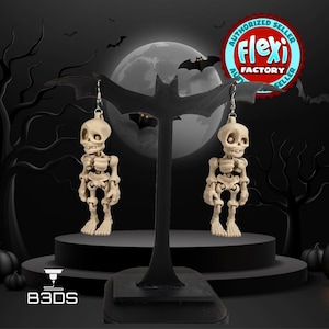 May include: A pair of skeleton earrings displayed on a black bat-shaped stand. The earrings are off-white and detailed, with a skull and articulated body. The background features a full moon, bats, and a spooky forest scene, perfect for Halloween.