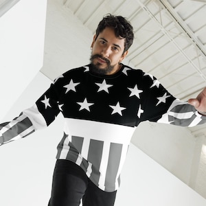 May include: A long-sleeved sweatshirt with a black and white star pattern on the upper section and striped design on the sleeves and lower front. The top has a crew neck and a relaxed fit, suitable for casual wear.