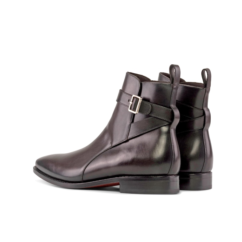 K&ouml;nnte beinhalten: Schwarze Leder-Ankle Boots mit spitzer Zehenpartie und silberner Schnalle. Die Stiefel haben einen Riemen und eine Zuglasche hinten. Die Sohle hat einen roten Akzent. Die H&ouml;he betr&auml;gt ca. 25 cm.