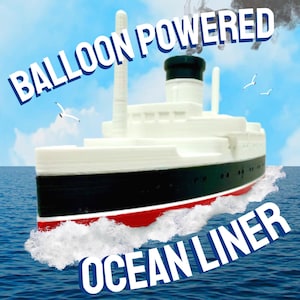 Könnte beinhalten: Ein Spielzeug-Ozeandampfer mit dem Text "BALLOON POWERED OCEAN LINER" vor blauem Himmel. Das Schiff ist weiß mit einem schwarzen und roten Rumpf, und weiße Wellen umgeben es. Möwen fliegen am Himmel.
