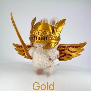 May include: A soft toy bunny wearing a gold helmet, wings, and holding a gold sword. The wings have a red and gold design. The word "Gold" is written in gold at the bottom of the image.