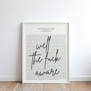 Pode incluir: Impressão emoldurada com borda branca, com fundo de página de livro. A sobreposição de texto diz "well the fuck aware" em uma fonte elegante e manuscrita. A impressão é exibida em um piso de madeira.