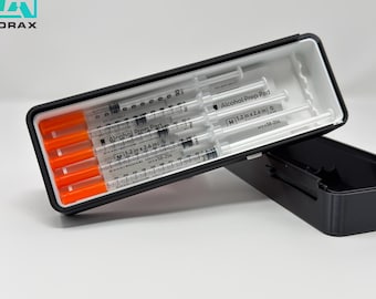 May include: A black rectangular case with a white interior, holding several syringes with orange caps. The case is open, revealing the contents, and the brand name "CALVORAX" is visible in the upper left corner.