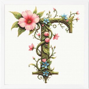May include: Cross-stitch design of the letter "T" adorned with pink and blue flowers, green leaves, and vines. The floral elements are arranged around the letter, creating a decorative and botanical theme. The background is white.