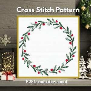 Könnte beinhalten: Ein Kreuzstichmuster mit einem Kranzdesign aus grünen Blättern und roten Beeren. Der Text "Cross Stitch Pattern" steht oben und "PDF instant download" unten. Der Kranz ist vor einem weißen Hintergrund.