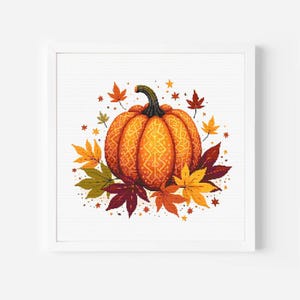 以下が含まれることがあります： カラフルな秋の葉に囲まれた、額縁に入ったピクセル化されたカボチャのイラスト。カボチャはオレンジ色でテクスチャパターンがあり、葉は赤、黄、緑の色合いです。アートワークは白い背景に設定されています。