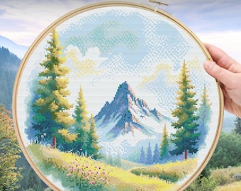 Puede incluir: Un bastidor de bordado circular de madera que contiene un patrón de punto de cruz de un paisaje montañoso con pinos, un prado y un cielo azul. El texto "Cross Stitch Pattern PDF" aparece en blanco en la parte superior de la imagen.