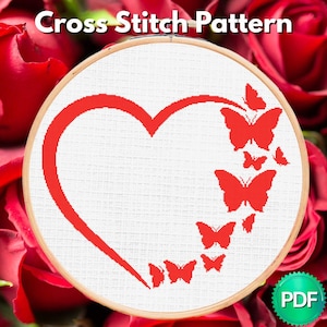 May include: Cross stitch pattern featuring a red heart and butterflies design. The design is on white fabric, framed in a wooden hoop. The text "Cross Stitch Pattern" is at the top.
