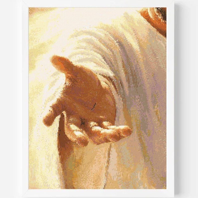 May include: A framed wall art print featuring a close-up of an outstretched hand reaching forward, rendered in warm golden and white tones. The image depicts a textured, fabric-like appearance with soft lighting, suggesting a figure draped in robes.
