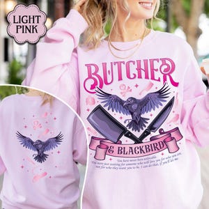 May include: Light pink sweatshirt with the word "BUTCHER" in pink script. A black raven graphic is centered below the word, with a cleaver and knife. The text "& BLACKBIRD" is below the graphic, with a quote at the bottom.