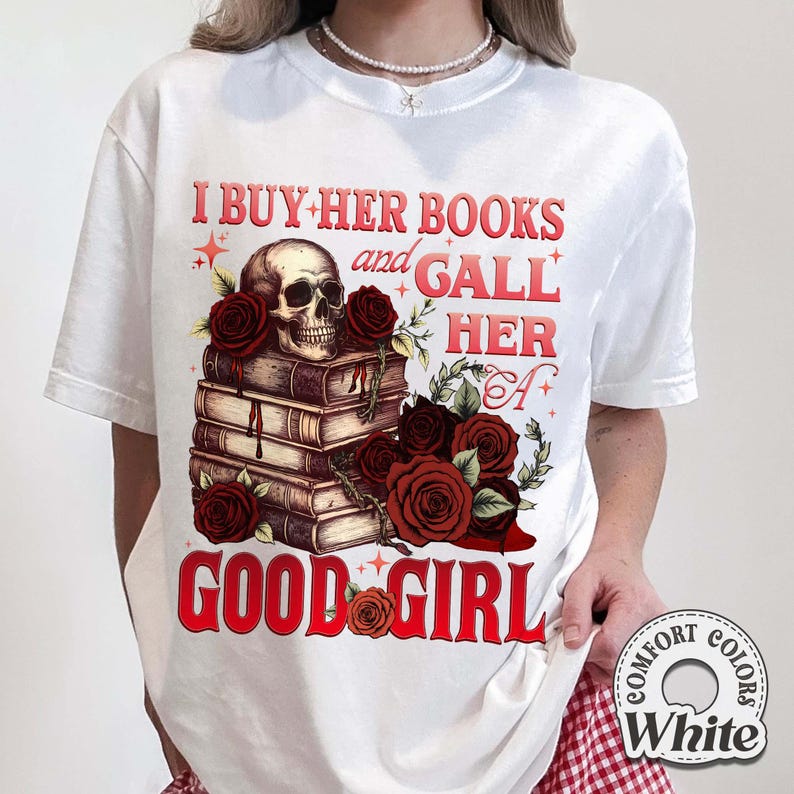 May include: White t-shirt with a graphic design featuring a skull atop a stack of books, surrounded by red roses. The text reads "I BUY HER BOOKS and GALL HER A GOOD GIRL" in red. The shirt is labeled "Comfort Colors White".
