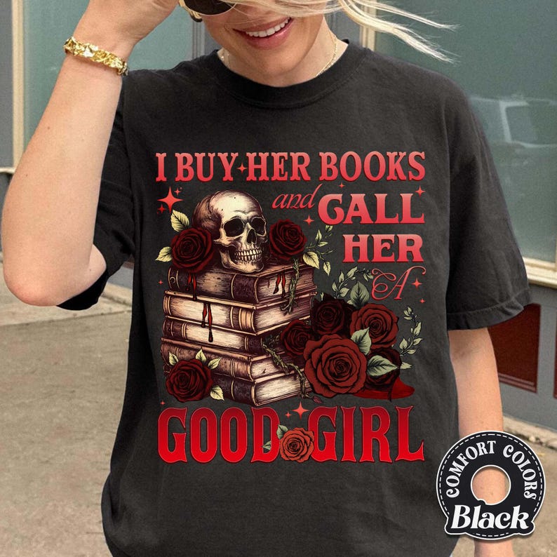 May include: Black t-shirt with a graphic design featuring a skull atop a stack of books, surrounded by red roses. The text reads "I BUY HER BOOKS and GALL HER A GOOD GIRL."