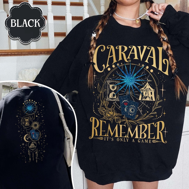 K&ouml;nnte beinhalten: Schwarzes Langarm-Sweatshirt mit goldenem und blauem Grafikdesign. Das Design enth&auml;lt das Wort "CARAVAL" &uuml;ber dem Wort "REMEMBER" und den Satz "IT'S ONLY A GAME". Die R&uuml;ckseite des Sweatshirts hat ein &auml;hnliches Design.