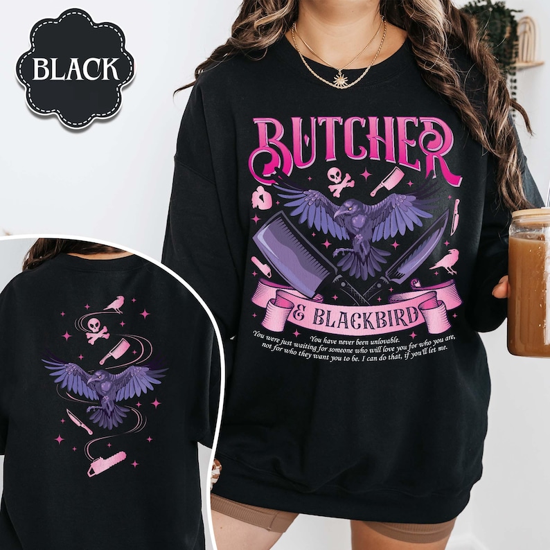 May include: Black sweatshirt with a graphic design featuring a raven, cleavers, and the text "BUTCHER & BLACKBIRD". The design includes pink and purple accents, with additional text at the bottom. The word "BLACK" is in a black oval.