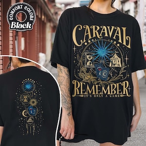 May include: Black t-shirt with a gold and blue graphic design featuring the word "CARAVAL" above "REMEMBER". The design includes a starburst, hourglass, playing cards, and a circus tent. The back of the shirt has a similar design.