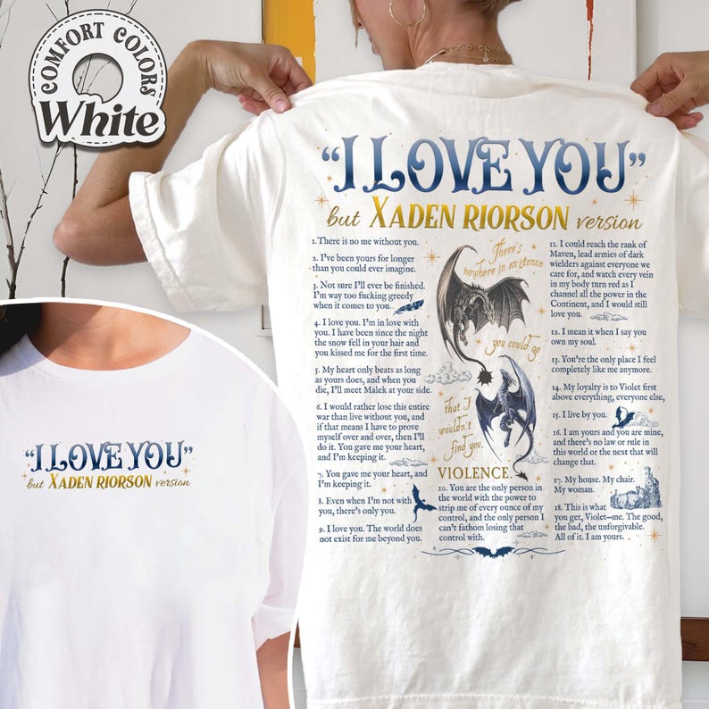 May include: White t-shirt with the text "I LOVE YOU" and "but Xaden Riorson version" in blue. The back of the shirt features a detailed graphic with text and illustrations of dragons and other elements. The shirt has a round neckline.