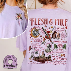May include: A light purple t-shirt with a graphic design featuring the text "FLESH & FIRE" and various illustrations. The design includes a wolf, a sword, and other fantasy-themed elements. The shirt also has the text "COMFORT COLORS" and "Orchid".