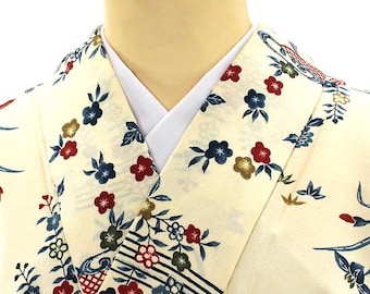 May include: Cream-colored kimono with a floral pattern in red, blue, and green. The kimono features a white collar and a decorative design along the edges. The fabric appears to be lightweight and suitable for warmer weather.