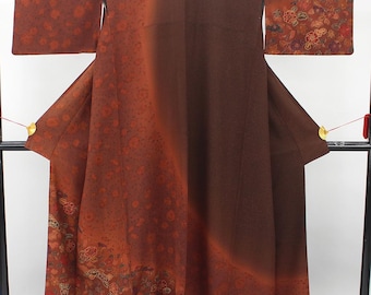 Può includere: Un kimono color marrone scuro e ruggine caratterizzato da una sfumatura di colore. Il capo presenta un dettagliato motivo floreale con piccoli fiori sulle maniche e sulle sezioni inferiori, nei toni del rosso, dell'arancione e dell'oro.