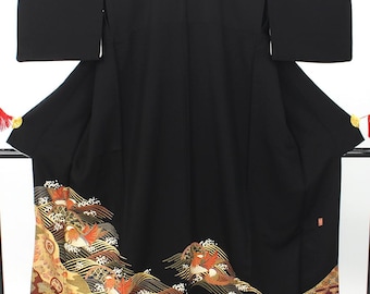May include: A black kimono with a detailed, colorful design at the hem. The design features birds, waves, and floral patterns in shades of orange, gold, and brown. The kimono has long sleeves and is displayed on a rack.
