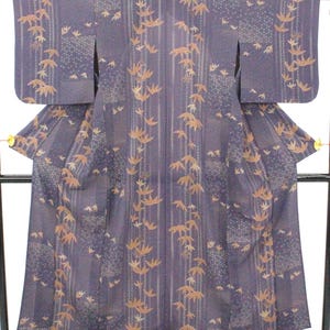 May include: A dark purple kimono featuring a repeating pattern of light brown bamboo leaves. The garment displays a vertical striped design interspersed with rectangular sections of a fine, dotted texture, creating a layered visual effect.