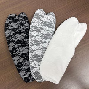 以下が含まれることがあります： 黒レース、白レース、無地の白の足袋ソックス3足。靴下はつま先が分かれたデザインで、柔らかく繊細な生地で作られています。レース模様は花柄です。