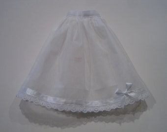 May include: A white tulle skirt with a white satin ribbon and lace trim. The skirt has a bow on the right side.