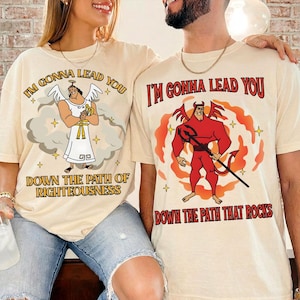 May include: Two beige t-shirts with the text "I'M GONNA LEAD YOU". One shirt features an angel graphic with the text "DOWN THE PATH OF RIGHTEOUSNESS". The other shirt has a devil graphic with the text "DOWN THE PATH THAT ROCKS".