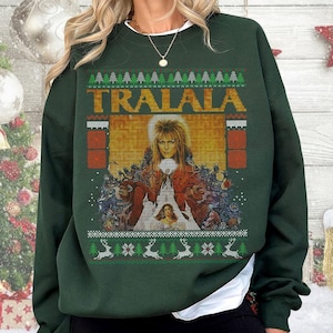 May include: A dark green sweatshirt featuring a graphic from the movie Labyrinth. The word "TRALALA" is across the top in orange letters. The graphic includes a portrait of David Bowie as Jareth the Goblin King. The bottom of the sweatshirt has a pattern of reindeer and trees.