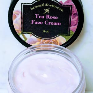 May include: A jar of Tea Rose Face Cream with a black lid. The lid features a label with the text "hernextlife.etsy.com" and "Tea Rose Face Cream" with floral accents. The jar contains a light pink cream, 4 oz.