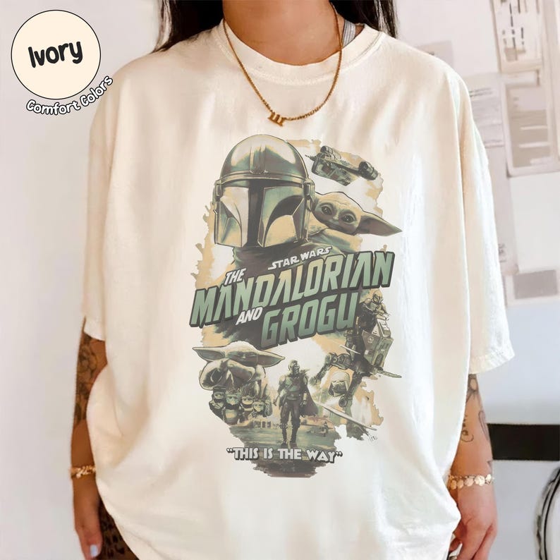 Pu&ograve; includere: T-shirt color avorio con grafica della serie Star Wars, "The Mandalorian and Grogu". Il design include immagini del Mandaloriano, Grogu e la scritta "This is the Way."
