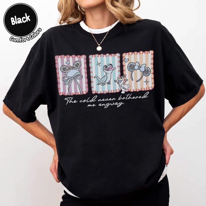 May include: Black t-shirt with three framed illustrations of characters and accessories. The text "The cold never bothered me anyway" is printed below the illustrations. The shirt has a crew neck and short sleeves.