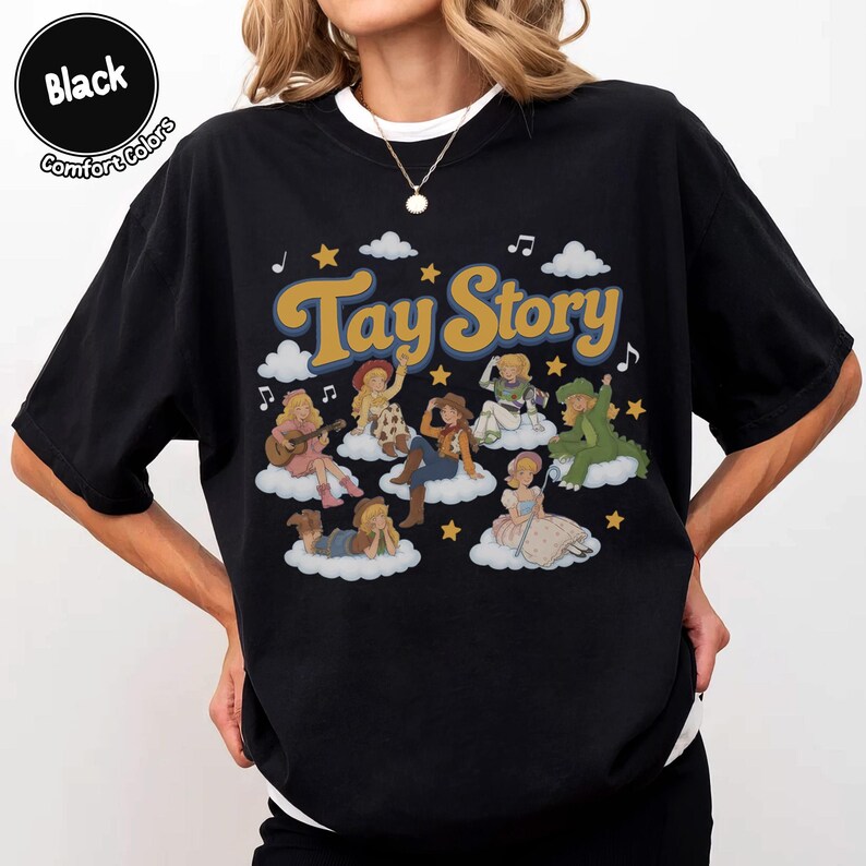 May include: A black t-shirt featuring the text "Tay Story" in a retro font. The graphic includes multiple illustrated figures dressed as various characters sitting on white clouds, surrounded by yellow stars and musical notes on a black background.
