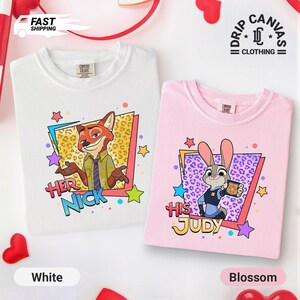 May include: White and blossom pink t-shirts featuring cartoon characters. The white shirt has a fox graphic with the text "Her Nick". The pink shirt has a bunny graphic with the text "His Judy". Both shirts have colorful star accents.