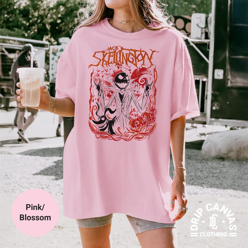 Puede incluir: Camiseta rosa claro con un dise&ntilde;o de Jack Skellington de Pesadilla antes de Navidad. El dise&ntilde;o presenta a Jack con un traje, calabazas y el texto "Jack Skellington" en rojo. La camiseta es de color rosa claro.