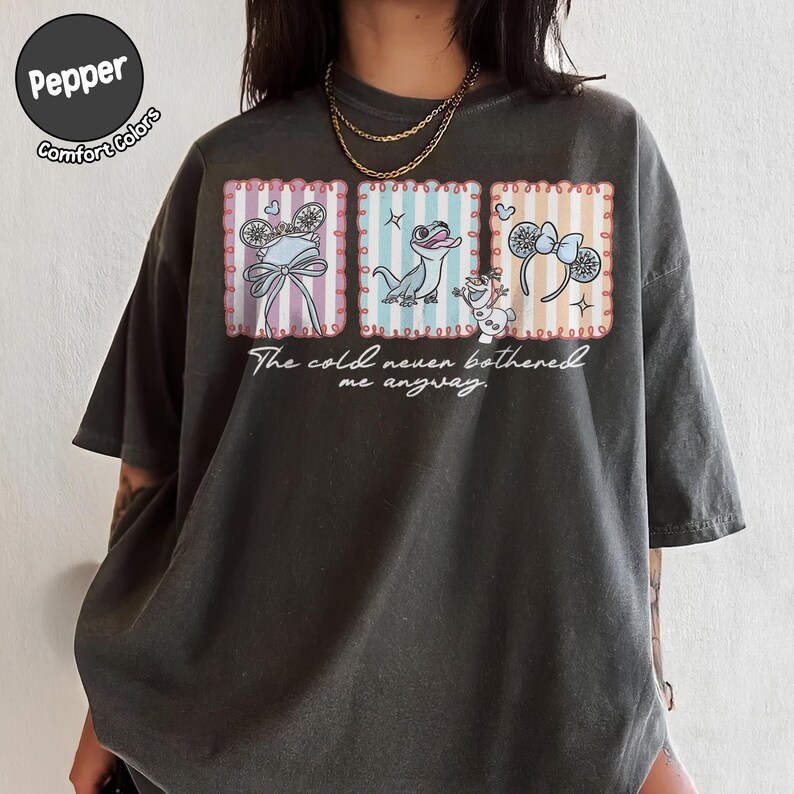 May include: Dark grey t-shirt with three framed illustrations of Disney characters and the text "The cold never bothered me anyway." The illustrations include a bow, a lizard, and a snowman.