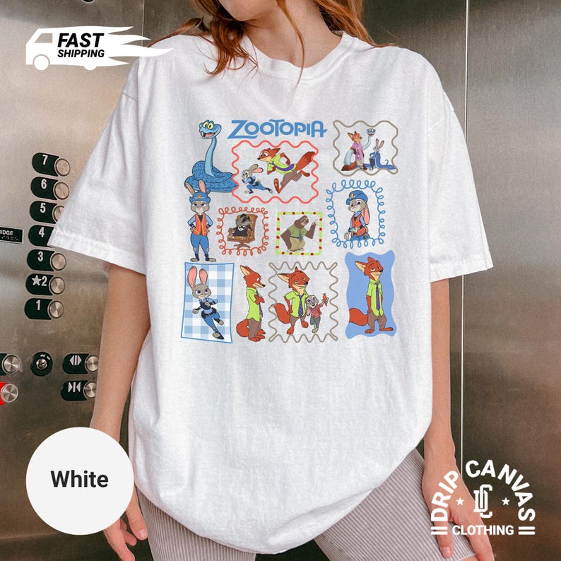May include: White t-shirt featuring a colorful Zootopia graphic. The design includes various characters from the animated film in framed illustrations. The shirt has short sleeves and a relaxed fit, perfect for casual wear.