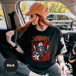 Puede incluir: Camiseta negra con un gr&aacute;fico de Jack Skellington de Pesadilla antes de Navidad. El dise&ntilde;o incluye a Jack con los brazos levantados, una calabaza y el texto "Jack Skellington". La camiseta es de Drip Canvas Clothing.