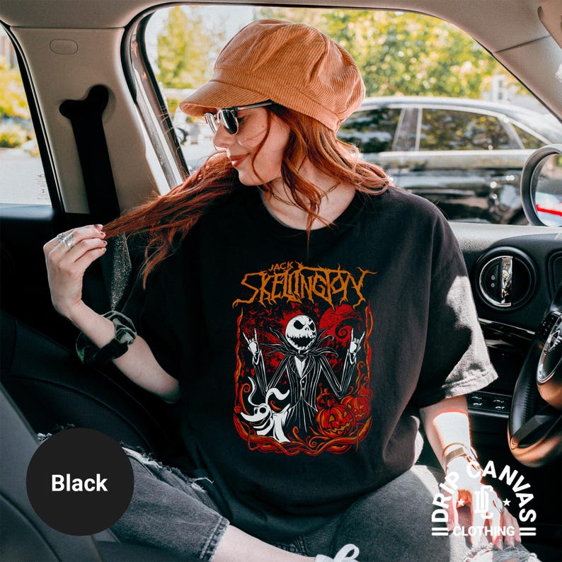 Puede incluir: Camiseta negra con un gr&aacute;fico de Jack Skellington de Pesadilla antes de Navidad. El dise&ntilde;o incluye a Jack con los brazos levantados, una calabaza y el texto "Jack Skellington". La camiseta es de Drip Canvas Clothing.