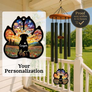 May include: A personalized dog paw-shaped wind chime. The paw print design features a stained-glass style sunset scene with a dog silhouette and the name "Cooper." The wind chime has black chimes and a wooden top.