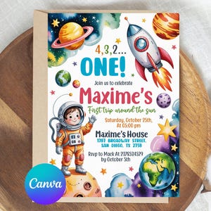 May include: An invitation card with a space theme. It features a cartoon astronaut, planets, a rocket, and the text "4,3,2... ONE!" and "Maxime's First trip around the sun". The card is on a wooden surface.
