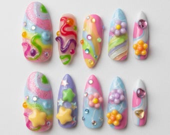 Puede incluir: Un conjunto de diez uñas artificiales decoradas con diseños variados. Las uñas presentan remolinos, flores, estrellas y gemas. Los colores incluyen rosa, azul, amarillo y verde. Cada uña mide aproximadamente 2,5 cm de largo.