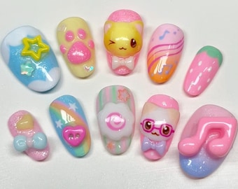 May include: A collection of ten colorful, decorated fingernails. Designs include a star, paw prints, a cat, musical notes, a strawberry, a bow, a rainbow, a flower, a cat with glasses, and a musical note.