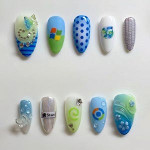 May include: A set of ten press-on nails featuring various designs including a Windows logo, a music note, a keyboard pattern, a Start button, and blue and green gradients with 3D butterfly, flower, and clear bubble embellishments.