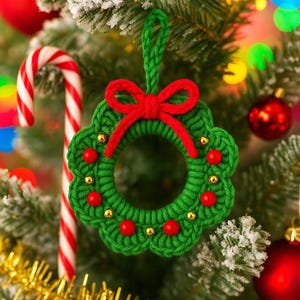 May include: A handmade green crochet Christmas wreath ornament with a red bow and red bead accents. The wreath is hanging on a Christmas tree with a candy cane and red ornaments in the background.