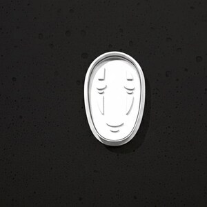 May include: A white, oval-shaped mask with a minimalist design, featuring two vertical lines for eyes and a curved line for a smile. The mask is set against a dark, textured background, creating a striking contrast.