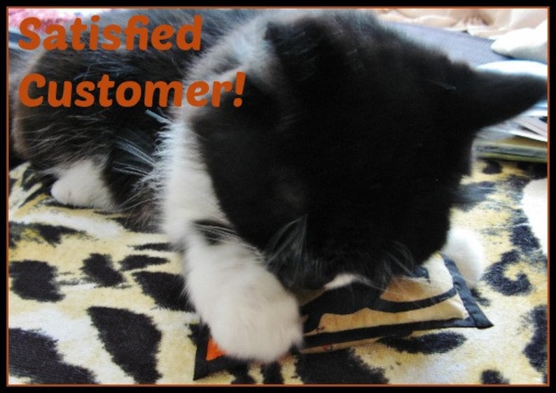 May include: A black and white cat is shown with the text "Satisfied Customer!" in orange. The cat is lying on a leopard print blanket and appears to be playing with a small toy.
