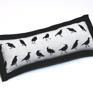May include: A black and white rectangular pillow with a black border and a repeating pattern of black crow silhouettes.